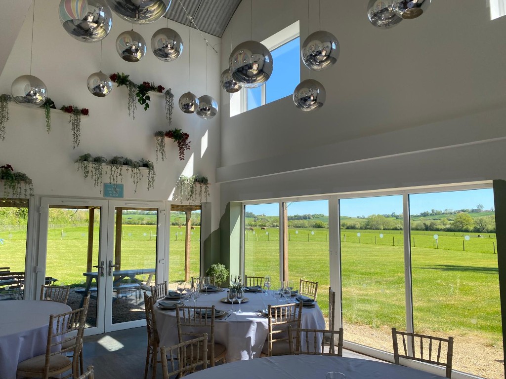 Large bright interior of The Barn at Stockham Marsh with full-height windows and countryside views.